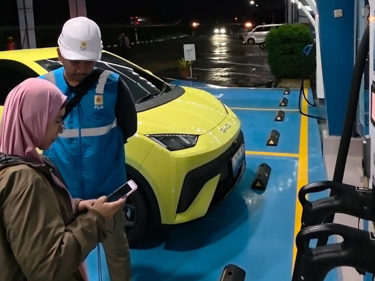 Pengguna EV asal Depok, Jawa Barat, Ufi Desi Fatmawati (kiri) ketika mengisi daya kendaraannya di Rest Area Tol 228A Kanci–Pejagan