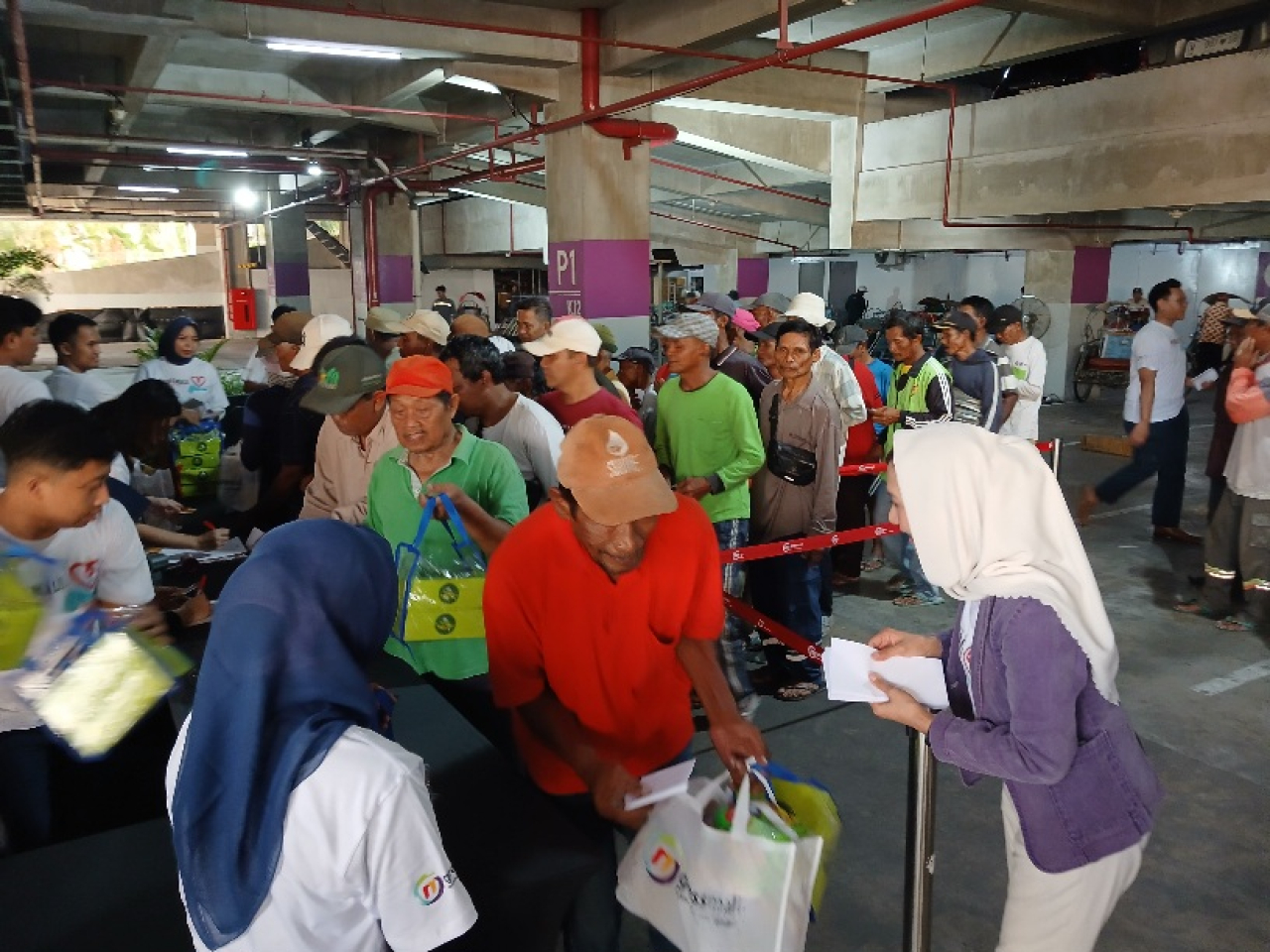 Direktur Sales PT Dharma Graha Utama, Ika Putri saat menyerahkan santunan kepada penarik becak yang mangkal di sekitar Gressmall